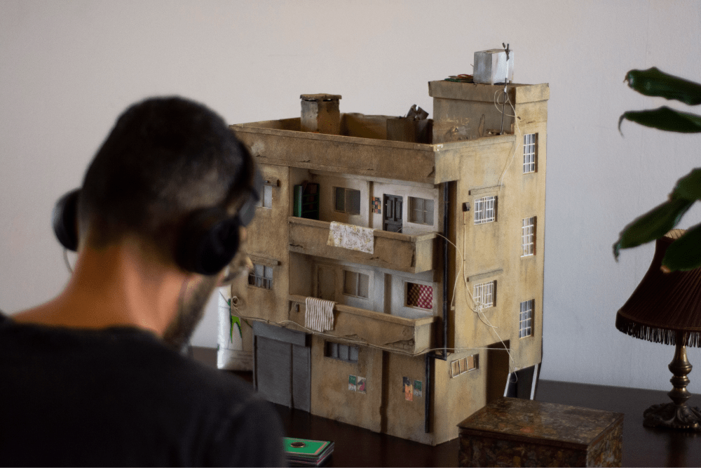 Basel Zaraa com auscultadores a observar o seu modelo detalhado de um edifício em miniatura. - Rui Palma