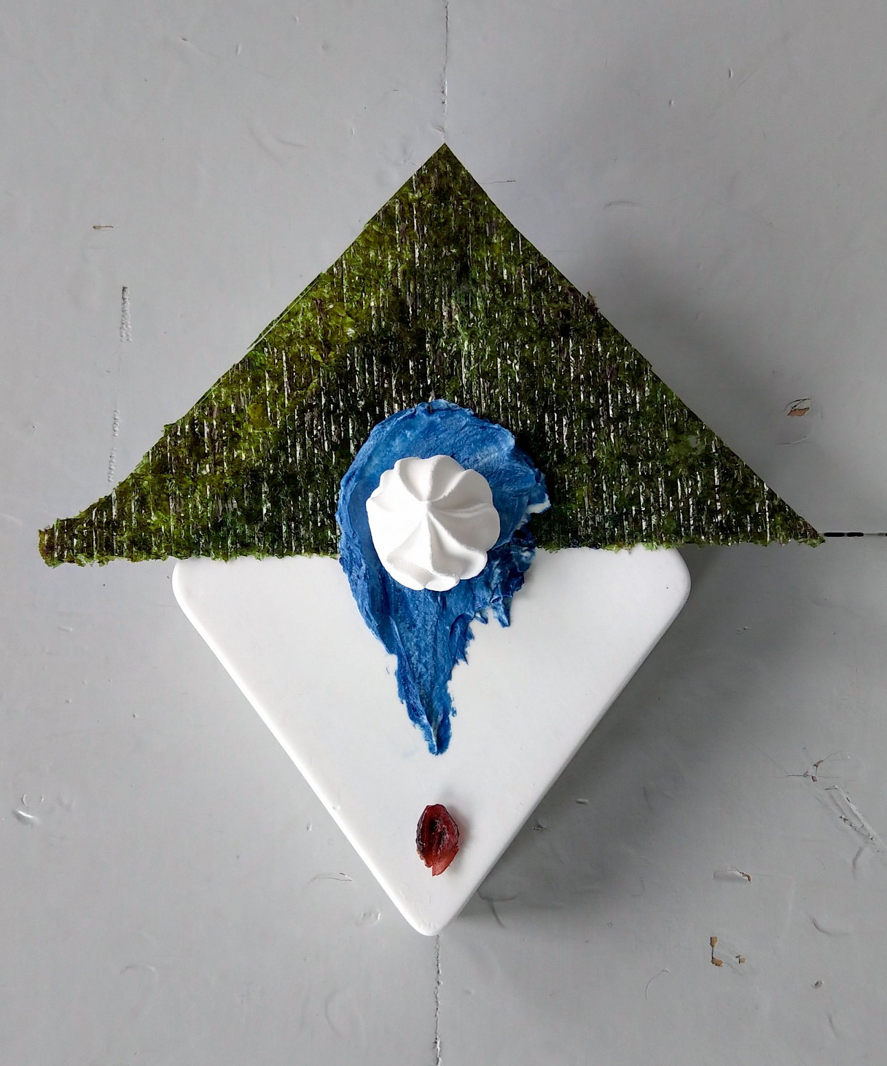 ALKANARA - Uma sobremesa artística com uma cobertura triangular verde, cobertura azul, uma colherada de chantilly e uma baga vermelha num prato branco. - ©Aru Ray Tormann / Celestial Bodies